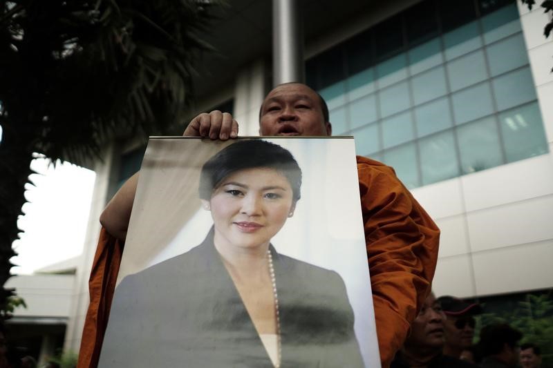 © Reuters. A buddhist monk holds a picture of Ousted former Thai prime minister Yingluck Shinawatra at the Supreme Court in Bangkok