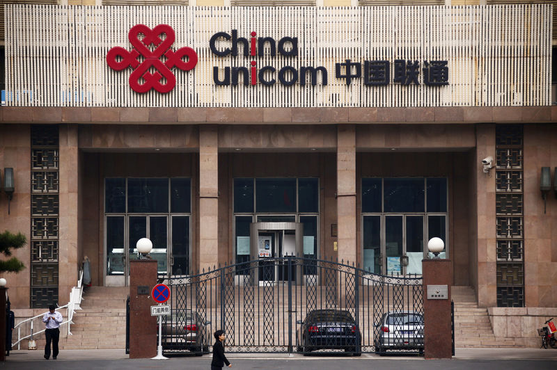 © Reuters. FILE PHOTO: People walk past outside the China Unicom office building in Beijing