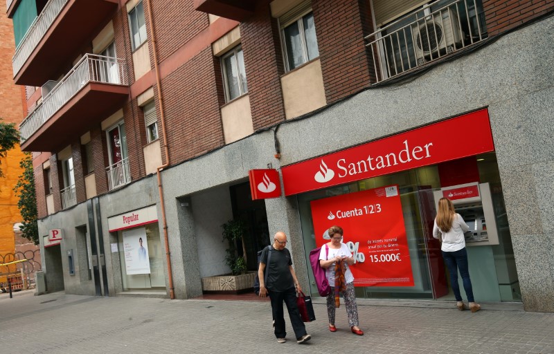© Reuters. A woman uses a Santander's cash dispenser next to a Banco Popular office as a couple walks past in Barcelona
