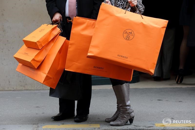 © Reuters. Пара с пакетами Hermes у магазина компании в Париже