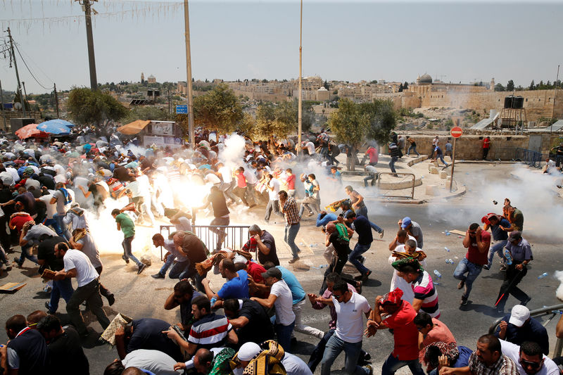 © Reuters. Palestinians react following tear gas that was shot by Israeli forces after Friday prayer on a street outside Jerusalem's Old city