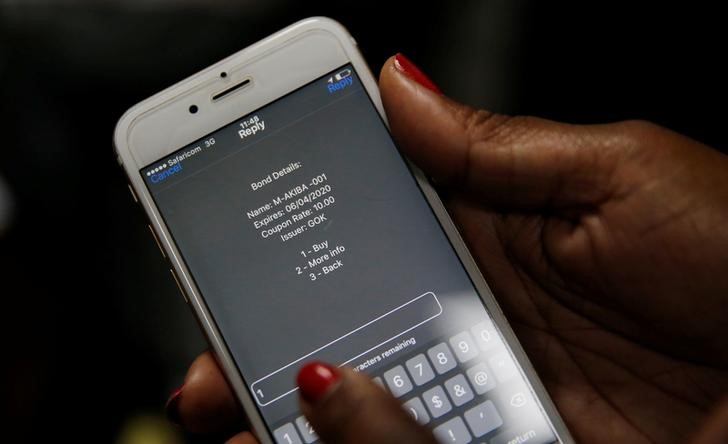 © Reuters. A delegate uses her cell phone to buy a M-Akiba bond during the launch of the first mobile-phone-based government bond at the Treasury building in Nairobi