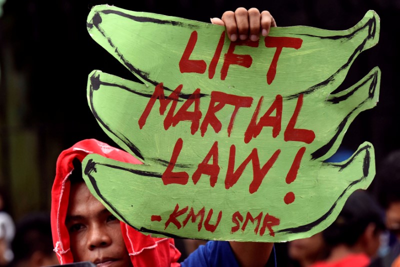 © Reuters. An anti martial law protestor hold a placard while protesting during the special session on the extension of martial law  at the House of Representatives in Quezon City, metro Manila