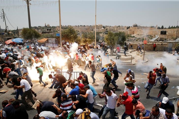 © Reuters. Jóvenes palestinos intentan escapar de los gases lacrimógenos lanzados por efectivos israelíes el viernes en enfrentamientos fuera de la Ciudad Antigua de Jerusalén