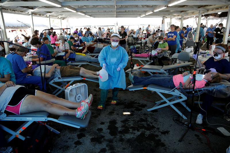 © Reuters. A volunteer walks past people receiving dental care at the Remote Area Medical Clinic in Wise, Virginia