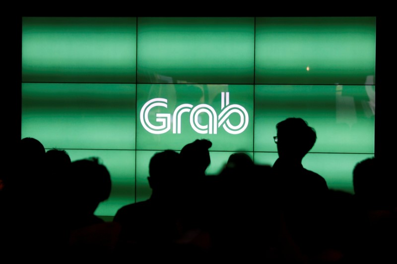© Reuters. FILE PHOTO - People wait for the start of Grab's fifth anniversary news conference in Singapore
