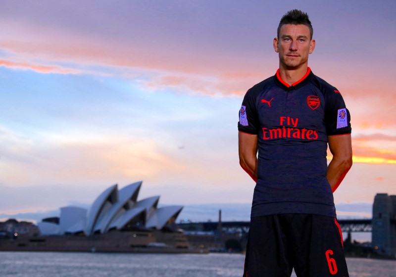 © Reuters. Soccer player Laurent Koscielny from English Premier League club Arsenal wears the 'Third Kit' for the 2017/2018 season as he stands in front of the Sydney Opera House in Sydney Harbour