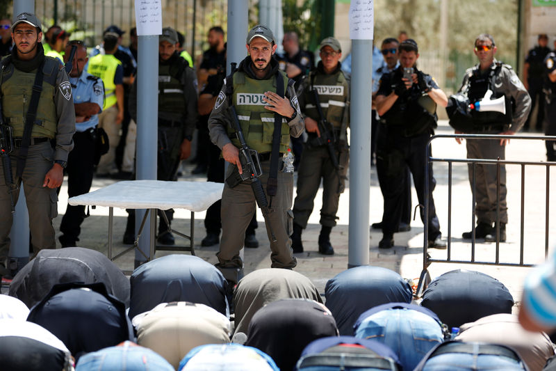 © Reuters. FILE PHOTO: Palestinians pray in front of Israeli policemen and newly installed metal detectors at an entrance to the compound known to Muslims as Noble Sanctuary and to Jews as Temple Mount in Jerusalem's Old City