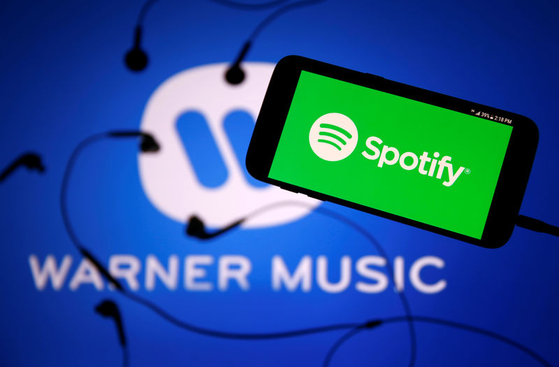© Reuters. A smartphone with a headset with Spotify logo are seen in front of a displayed Warner Music logo in this illustration picture