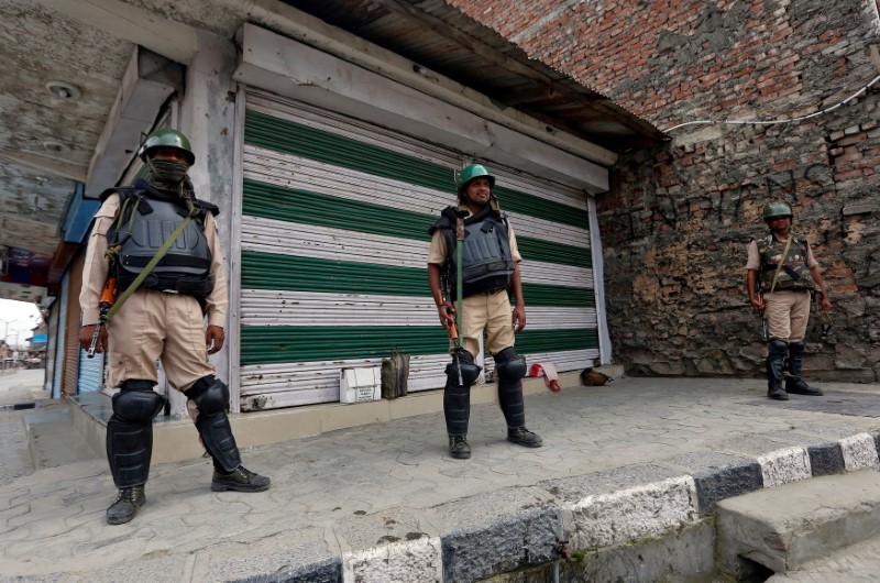 © Reuters. Indian policemen stand guard in front of closed shops during a curfew in the downtown area of Srinagar