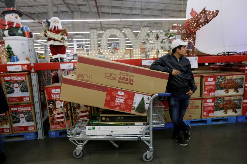 © Reuters. FILE PHOTO: A shopper waits next to his cart with television screens and other items during a shopping season, 