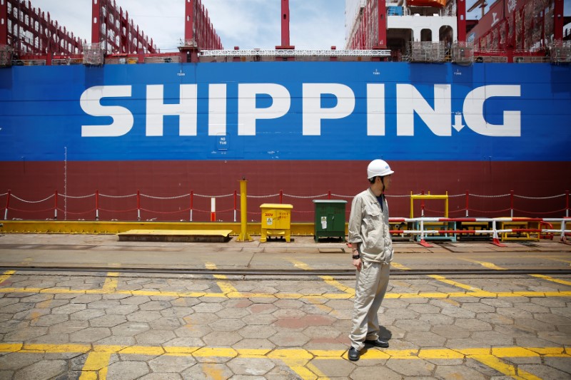 © Reuters. A labourer stand in front a new ship at Shanghai Waigaoqiao Shipbuilding Co., Ltd. in Shanghai