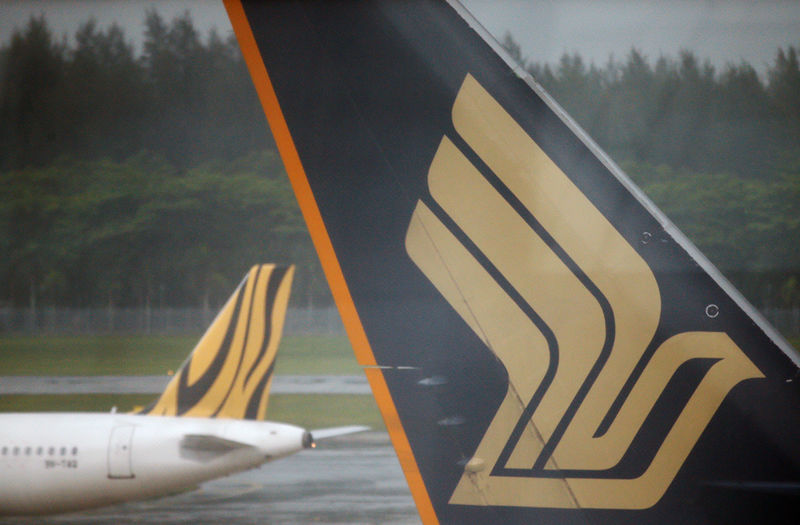 © Reuters. FILE PHOTO: A Tiger Airways plane passes a Singapore Airlines plane sitting on the tarmac at Changi Airport in Singapore