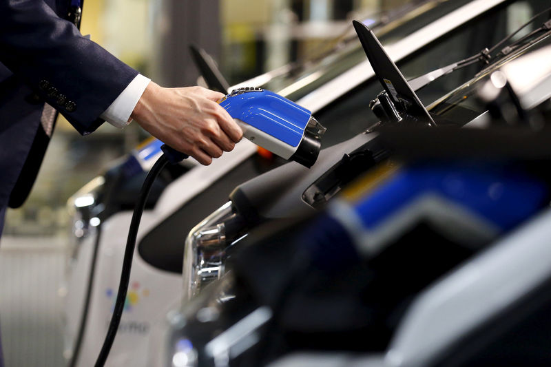 © Reuters. FILE PHOTO: A staff member plugs a charger cable into Toyota's i-Road electric vehicle in Tokyo