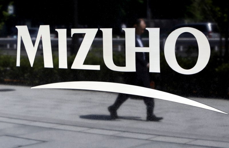 © Reuters. FILE PHOTO: Pedestrian is reflected in a sign showing the logo of the Mizuho Financial Group Inc. outside its headquarters in Tokyo
