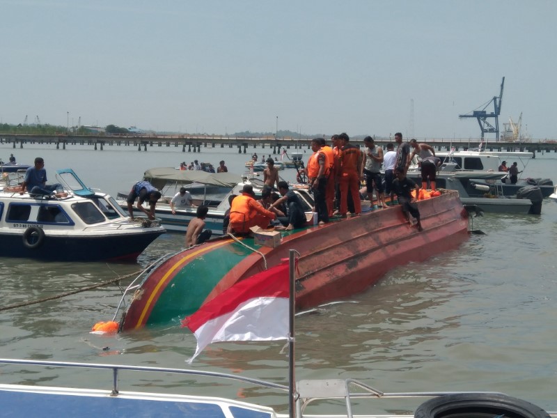 © Reuters. People stand atop a capsized boat near Tarakan