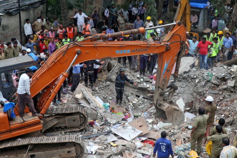 © Reuters. Bombeiros e funcionários de resgate removem destroços de prédio que desmoronou em Mumbai, na Índia