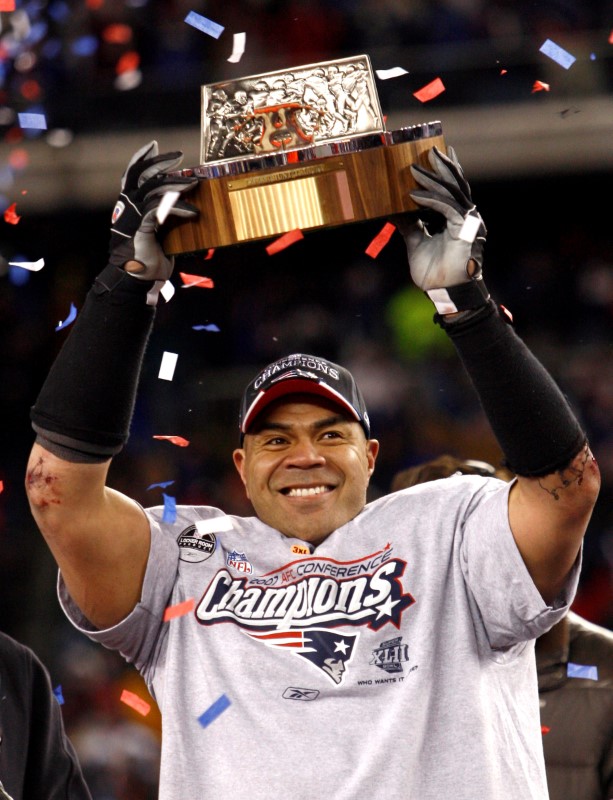 © Reuters. FILE PHOTO - New England Patriots Seau holds Lamar Hunt Trophy after defeating San Diego Chargers in NFL's AFC Championship in Foxborough