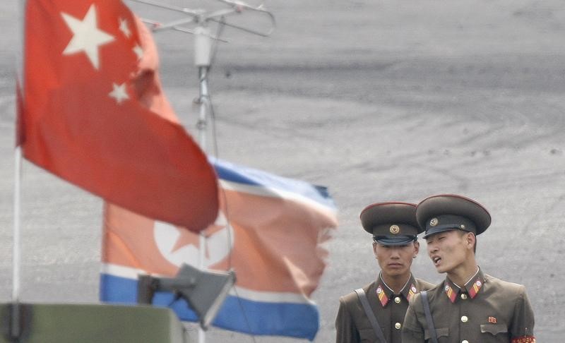 © Reuters. FILE PHOTO: North Korean soldiers chat as they stand guard behind national flags of China and North Korea on the banks of Yalu River, near the North Korean town of Sinuiju