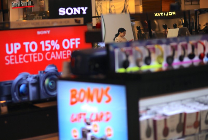 © Reuters. A shopper can be seen reflected in a mirror near electronic products on sale at a retail store located in a shopping mall in Sydney, Australia