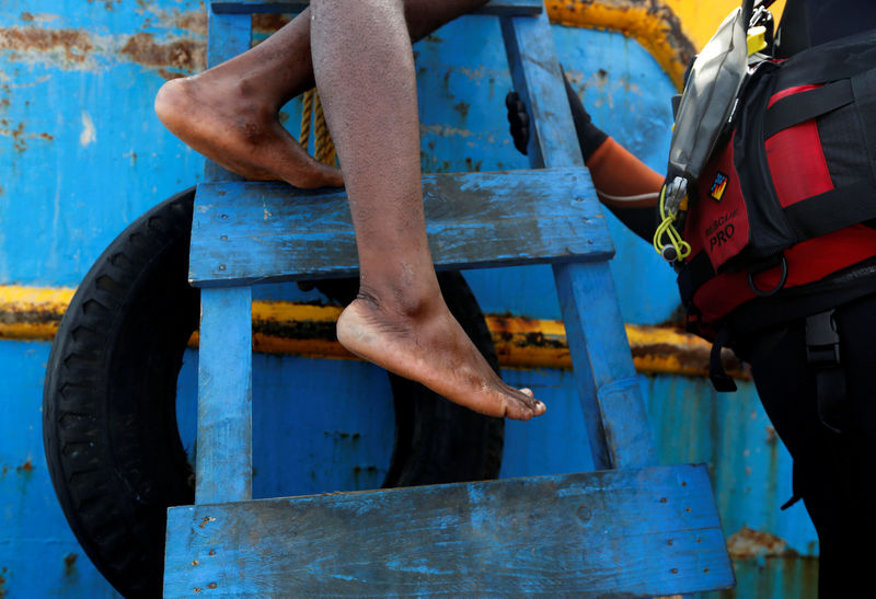 © Reuters. FILE PHOTO: Rescued migrant climbs down from a Tunisian fishing vessel onto a boat from the Malta-based NGO Migrant Offshore Aid Station (MOAS)