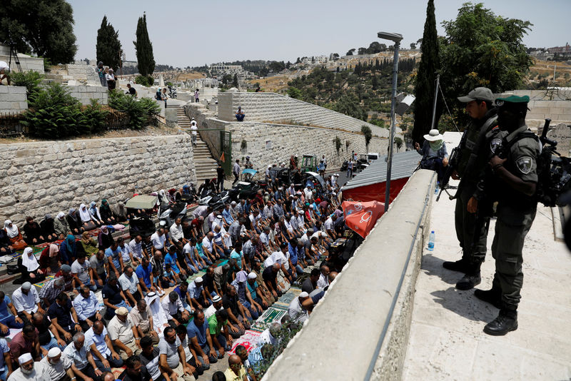 © Reuters. FILE PHOTO: Israeli border police officers stand guard as Palestinians pray at Lion's gate, an entrance to Jerusalem's Old City, in protest over Israel's new security measures at the compound housing al-Aqsa mosque