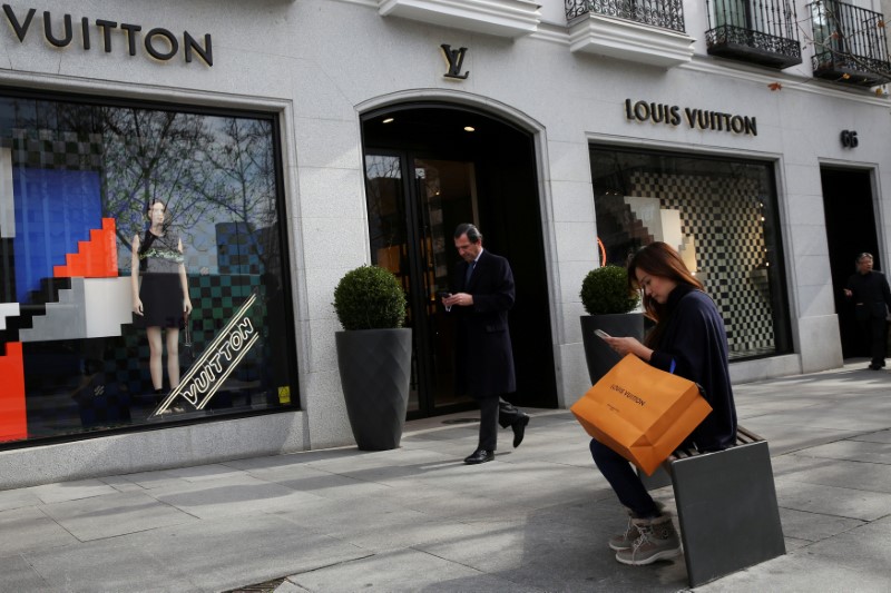 © Reuters. FILE PHOTO: A woman checks her phone after shopping at a Louis Vuitton store in the upscale shopping Serrano Street in central Madrid