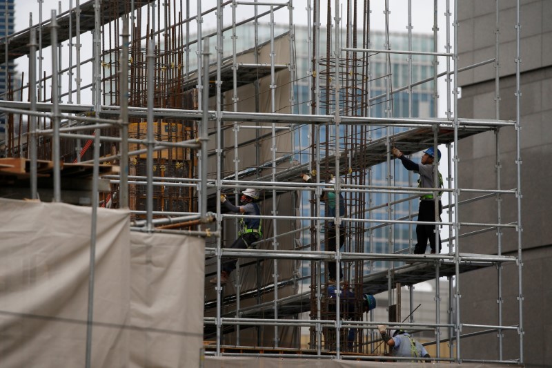 © Reuters. Workers labour on steel frames at a construction site in central Seoul