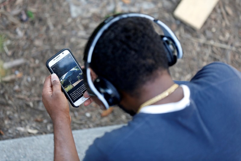 © Reuters. FILE PHOTO: A man looks at his Samsung cell phone in a park in Los Angeles