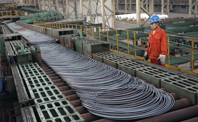© Reuters. A labourer looks at steel coils next to a production line of Dongbei Special Steel Group Co., Ltd., in Dalian
