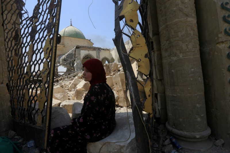 © Reuters. A displaced woman sits near the ruined Grand al-Nuri Mosque in the Old City of Mosul