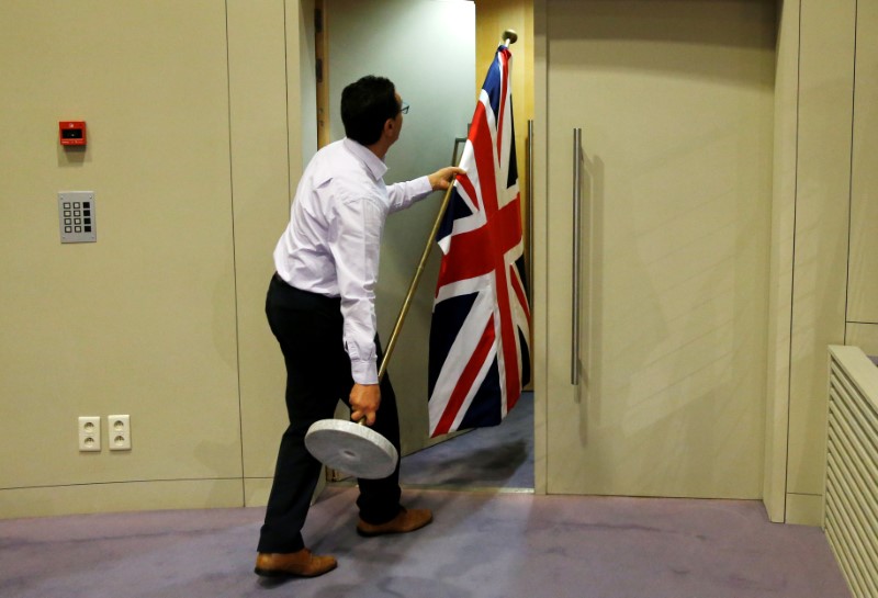 © Reuters. An official carries a Union Jack flag ahead of a news conference by Britain's Secretary of State for Exiting the European Union Davis and EU's chief Brexit negotiator Barnier in Brussels