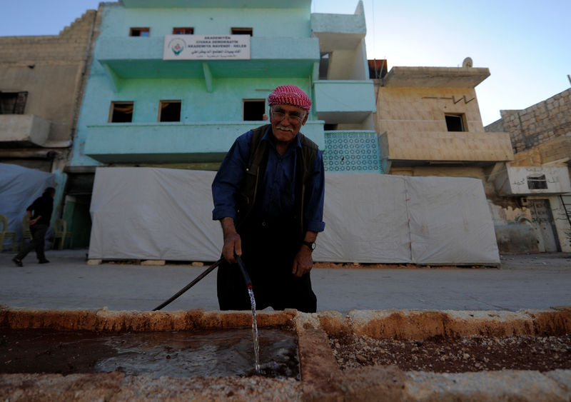 © Reuters. A kurdish man is seen in front of  "Democratic Community Academy" in Aleppo's Sheikh Maqsoud neighbourhood