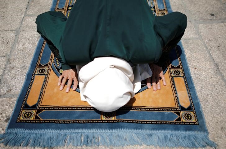 © Reuters. A Palestinian woman prays outside the compound known to Muslims as Noble Sanctuary and to Jews as Temple Mount, just outside Jerusalem's Old City