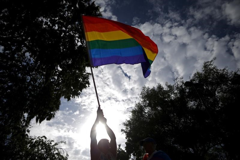 © Reuters. A man waves an LGBT equality rainbow flag at a celebration rally in West Hollywood, California,