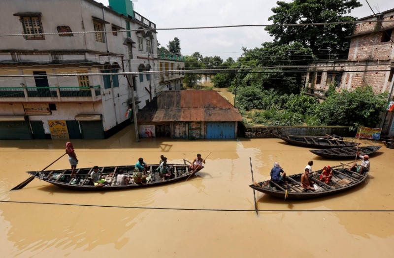 © Reuters. People use boats as they try to move to safer places along a flooded street in West Midnapore district