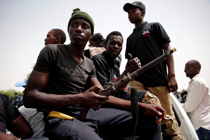 © Reuters. Members of the local militia, otherwise known as CJTF, sit in the back of a truck during a patrol in Maiduguri