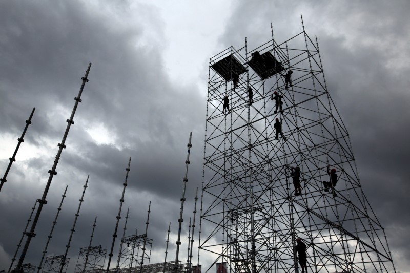 © Reuters. FILE PHOTO: Workers are seen in silhouette as they construct scaffolding in the port of Cannes