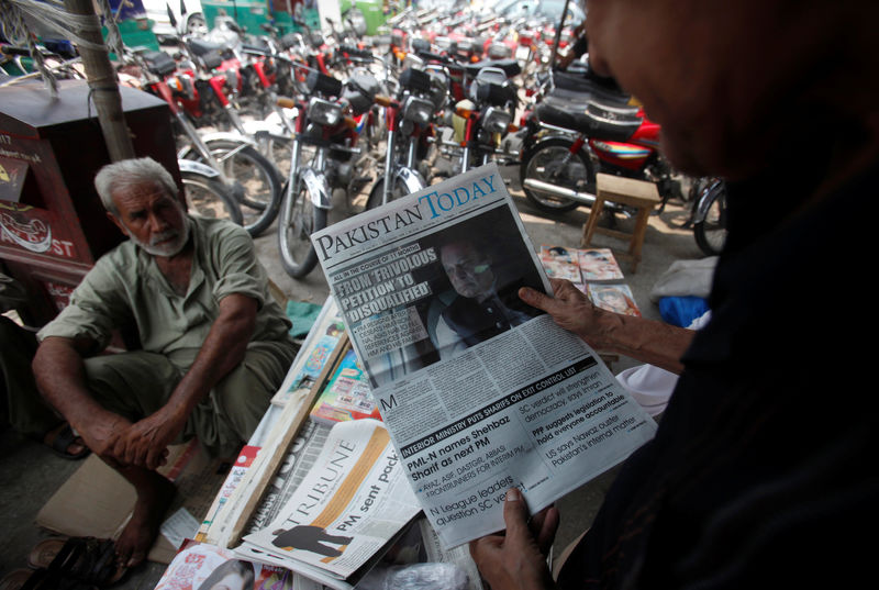 © Reuters. A man reads a newspaper with news about the disqualification of Pakistan's PM Sharif by the Supreme Court, at a news stand in Peshawar