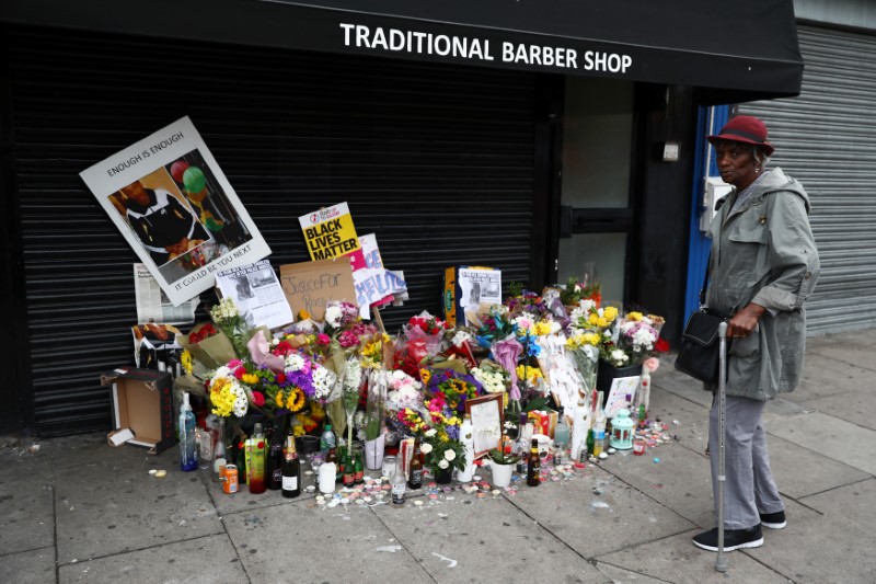 © Reuters. A woman looks at floral tributes laid after the death of Rashan Charles outside a shop in east London