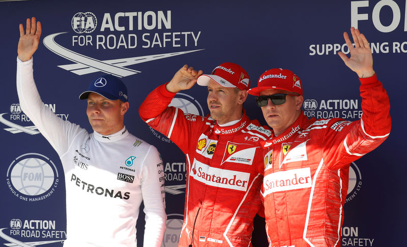 © Reuters. Los pilotos de Ferrari Sebastian Vettel (ctro) y Kimi Raikkonen (dcha) celebran tras lograr los dos primeros puestos de la parrilla de salida del Gran Premio de Hungría junto a Valtteri Bottas (Mercedes), tercero.