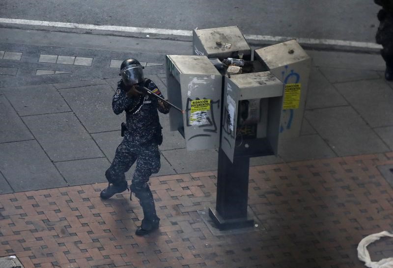 © Reuters. Un miembro de las fuerzas de seguridad de Venezuela apunta su arma durante enfrentamientos con manifestantes opositores en Caracas