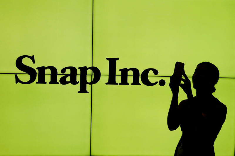 © Reuters. FILE PHOTO - A woman stands in front of the logo of Snap Inc. on the floor of the New York Stock Exchange in New York City