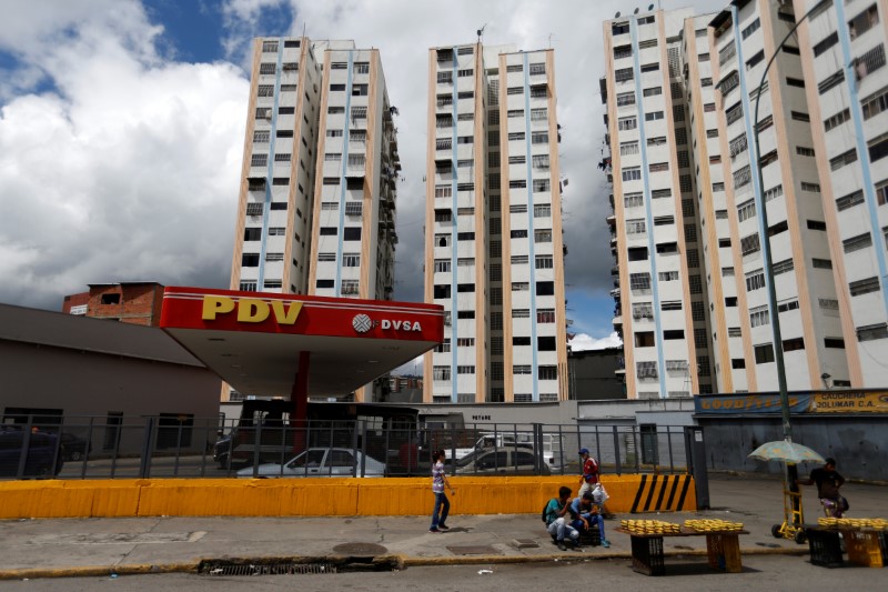 © Reuters. Pedestrians walk next to a PDVSA gas station in Caracas