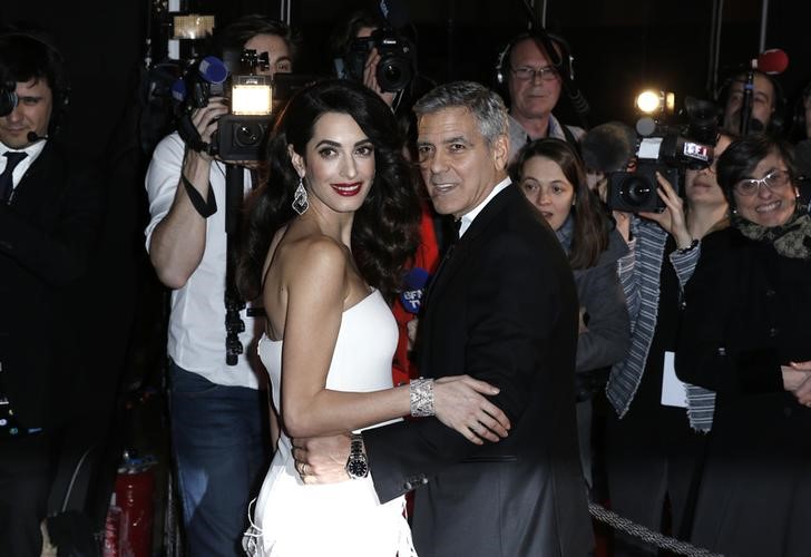 © Reuters. George Clooney e sua mulher Amal posam durante cerimônia em Paris