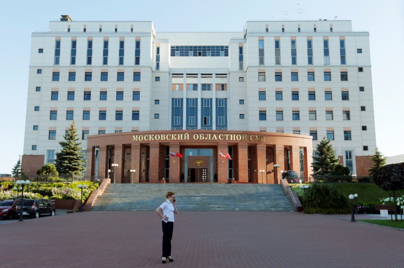 © Reuters. A woman speaks on her mobile phone outside the Moscow regional court building, where three people being taken to trial for robbery and murder were shot dead after they grabbed side-arms from court security officers in an attempt to escape, outside Moscow