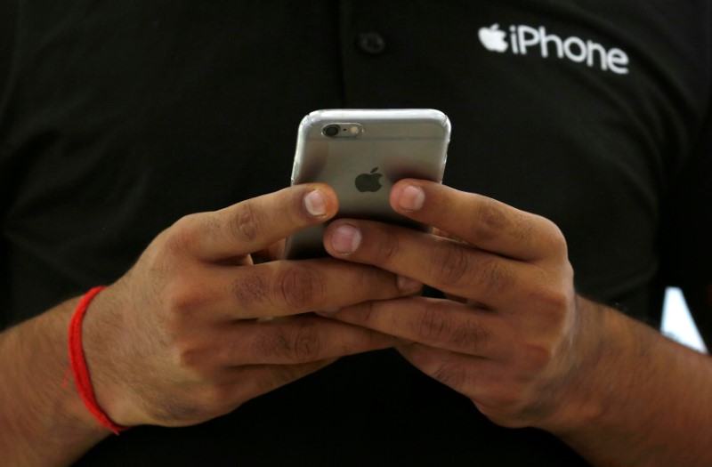 © Reuters. FILE PHOTO: A salesman uses his iPhone at a mobile phone store in New Delhi