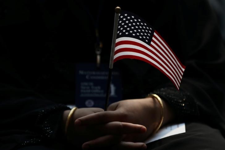 © Reuters. FILE PHOTO: An immigrant woman holds a U.S. flag during a U.S. Citizenship and Immigration Services Naturalization ceremony in the New York Public Library in New York