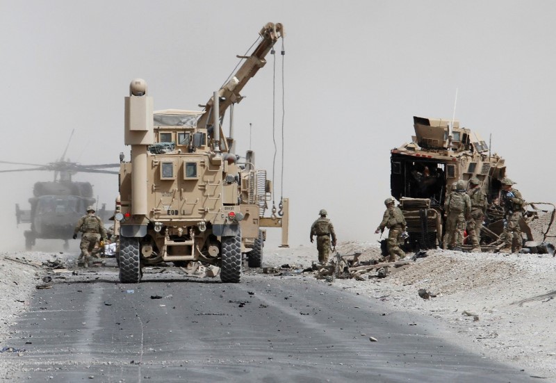 © Reuters. U.S. troops assess the damage to an armoured vehicle of NATO-led military coalition after a suicide attack in Kandahar province