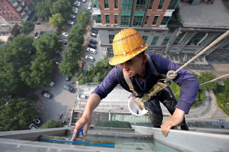 © Reuters. A worker cleans the windows of an apartment block in Beijing